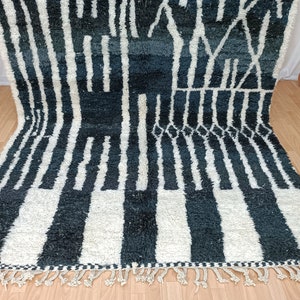 May include: A black and white Moroccan rug with a geometric pattern. The rug has a fringe border and is made of wool.