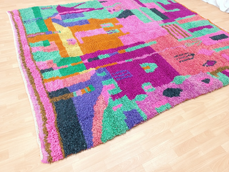 K&ouml;nnte beinhalten: Ein bunter, abstrakter Teppich mit einem geometrischen Muster in Pink, Gr&uuml;n, Lila und Orange. Der Teppich ist aus einem weichen, flauschigen Material.