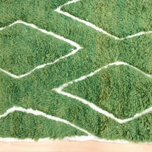 May include: Green and white patterned rug with a fuzzy texture. The rug has a diamond pattern with white lines.