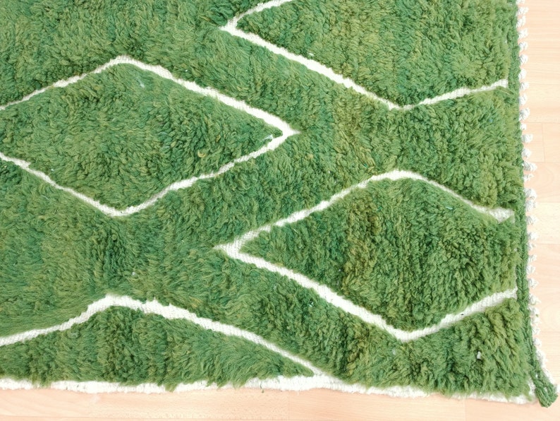May include: Green and white patterned rug with a fuzzy texture. The rug has a diamond pattern with white lines.