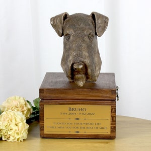 May include: A wooden pet urn with a bronze dog head sculpture on top. The urn has a gold plaque with the inscription "BRUNO 5/04/2004-9/02/2022 I LOVED YOU YOUR WHOLE LIFE I WILL MISS YOU FOR THE REST OF MINE".