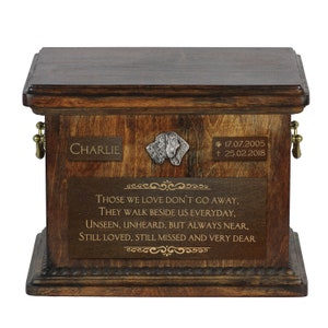 May include: A wooden pet urn with a brass plaque that reads "CHARLIE * 17.07.2005 † 25.02.2018". The urn also features a metal dog figurine and a quote that reads "Those we love don't go away, they walk beside us everyday, unseen, unheard, but always near, still loved, still missed and very dear."