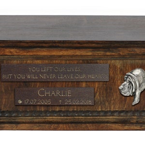 Könnte beinhalten: Dunkle Holz-Tierurne mit Gravuren: "YOU LEFT OUR LIVES, BUT YOU WILL NEVER LEAVE OUR HEARTS" und "CHARLIE" mit Daten. Auf der Seite befindet sich ein Metallrelief eines Basset Hounds. Dekorative Basis.