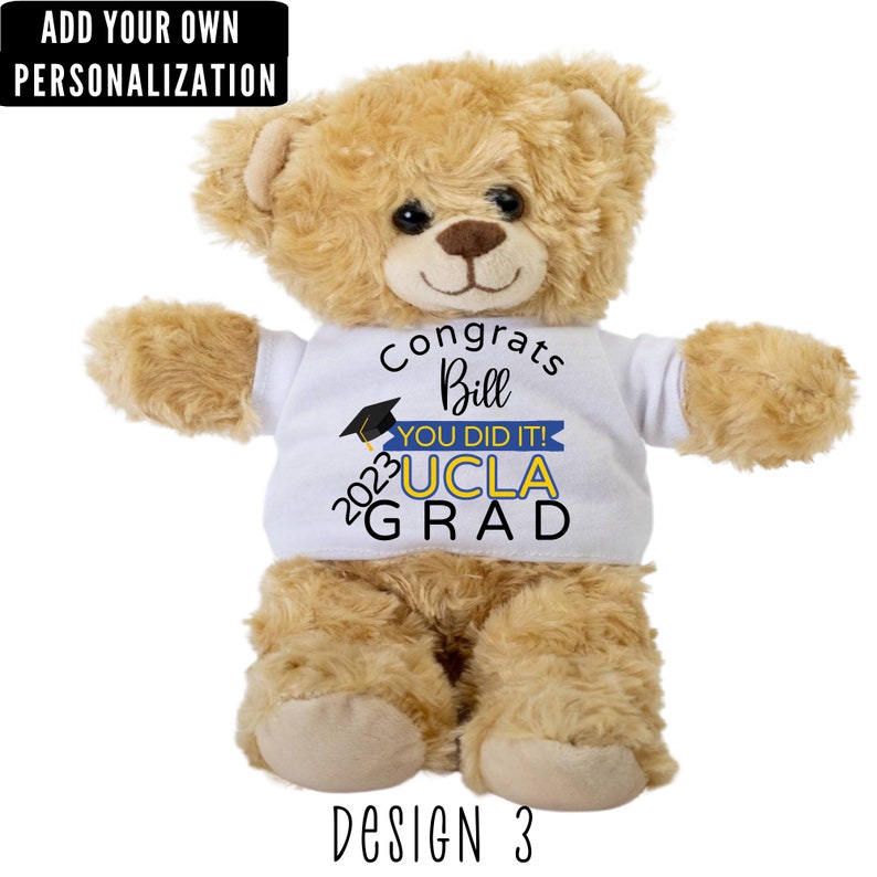 Puede incluir: Un oso de peluche marr&oacute;n que lleva una camiseta blanca con el texto "Congrats Bill You Did It! 2023 UCLA GRAD" en letras azules, amarillas y negras. El oso est&aacute; sentado sobre un fondo blanco. Dise&ntilde;o 3.
