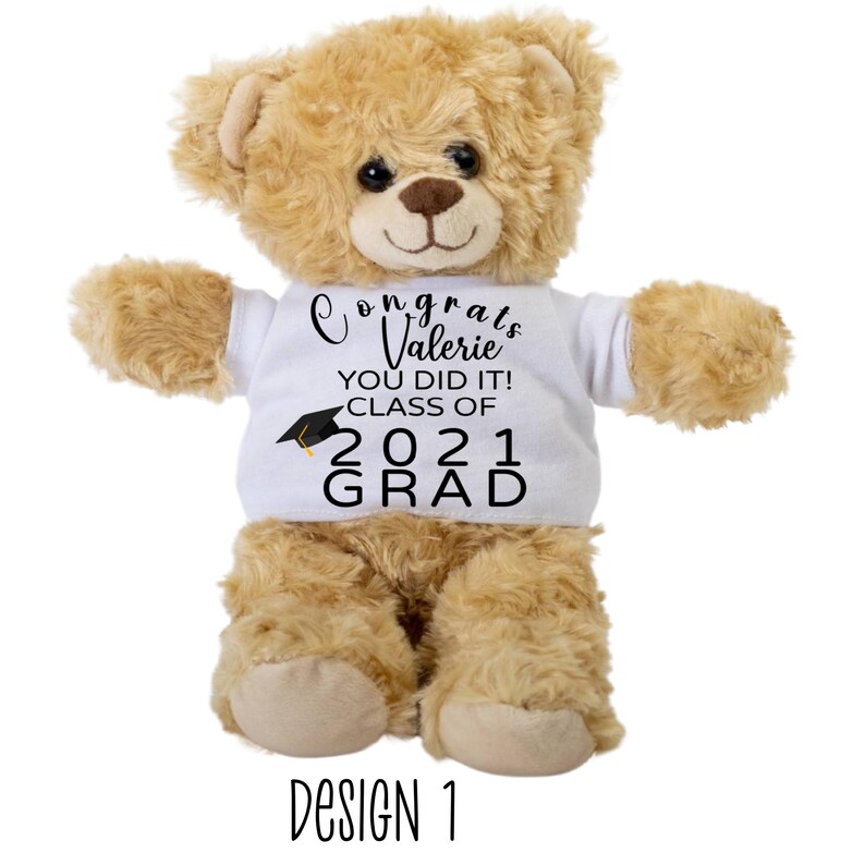 Puede incluir: Un oso de peluche marr&oacute;n que lleva una camiseta blanca con el texto "Congrats Valerie You Did It! Class of 2021 Grad" impreso en negro. Un gorro de graduaci&oacute;n negro est&aacute; sobre el texto "Class of".