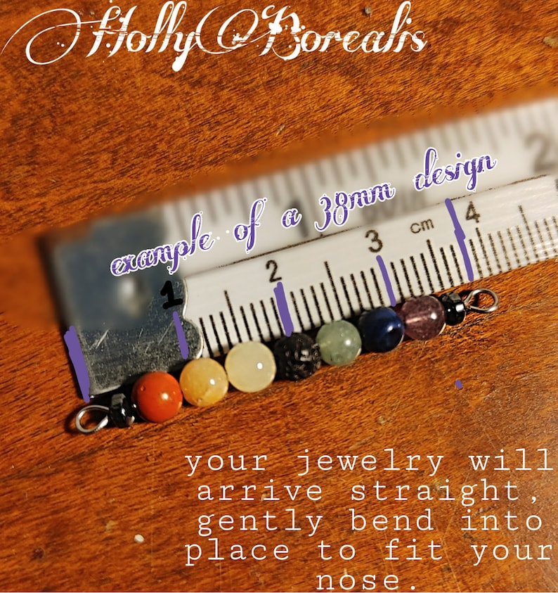 May include: A close-up of a jewelry piece with colorful beads, including orange, yellow, black, green, blue, purple, and clear beads. The text "example of a 38mm design" is visible. The text "your jewelry will arrive straight, gently bend into place to fit your nose" is also visible.