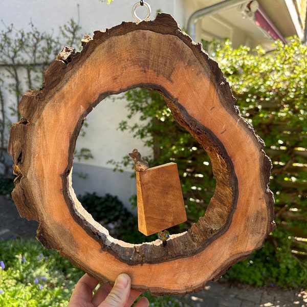 Windfänger aus einer großen Baumscheibe Nussbaum Holz mit einer kleinen fröhlichen Nana Bronze Skulptur