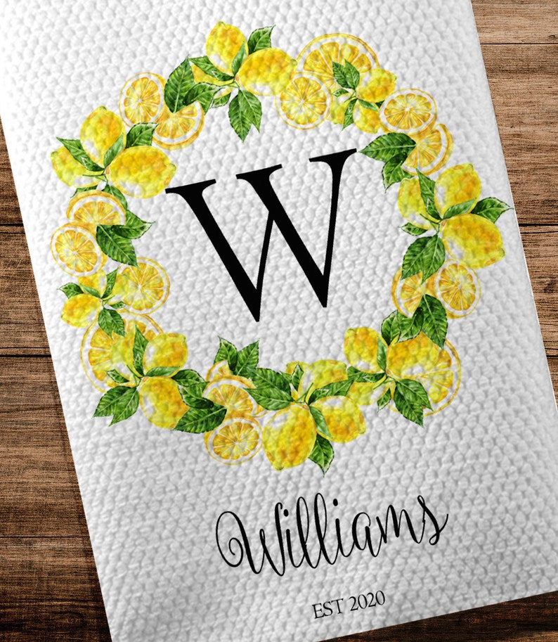 May include: White kitchen towel with a lemon wreath design. The wreath surrounds a large black letter "W". The word "Williams" is written in cursive below the letter, with "EST 2020" underneath.