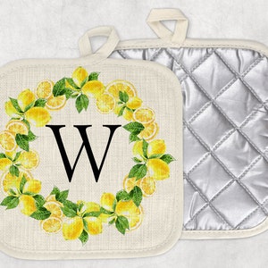 May include: Two square pot holders. One features a lemon wreath design with the letter "W" in the center. The other has a quilted silver lining. Both have a loop for hanging. The pot holders are cream-colored.