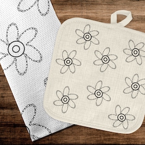Peut inclure: Un dessous de plat en coton blanc avec un motif floral noir. Le dessous de plat a une boucle pour l'accrocher. Le motif est composé de petites fleurs avec un cercle au centre.