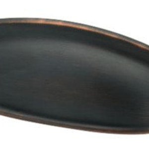 May include: A dark bronze oval cabinet pull with a smooth, slightly curved surface. The pull has a slightly raised edge around the perimeter.