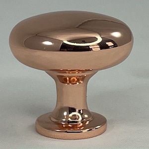 May include: A polished copper cabinet knob with a rounded top and a short, wide base.