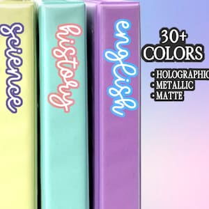 May include: Four colorful binders labeled "math", "science", "history", and "english". The binders are pink, yellow, teal, and purple. Text on the right says "30+ COLORS", "HOLOGRAPHIC", "METALLIC", and "MATTE". A logo is in the bottom left.