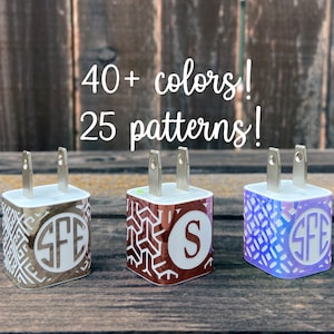 May include: Three phone chargers with personalized designs. The chargers are white with a silver trim and have different patterns and monograms. The text on the chargers reads "SFE" and "S".