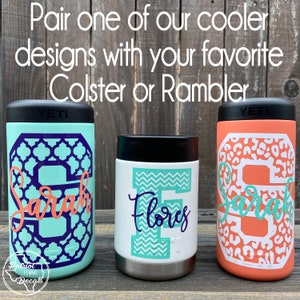 Op de afbeelding: Drie ge&iuml;soleerde drankhouders met zwarte deksels. E&eacute;n is mintgroen met een paars geometrisch ontwerp en de naam "Sarah" in koraal. Een andere is wit met een turquoise zigzagontwerp en de naam "Flores" in marineblauw. De derde is koraal met een luipaardprint en de naam "Sarah" in turquoise.