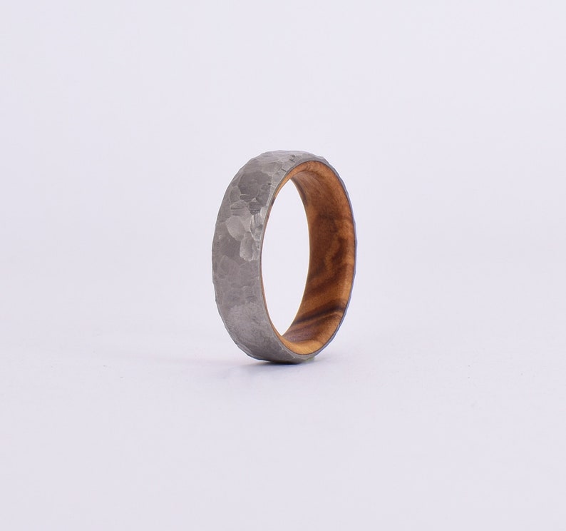 Anello in titanio battuto esterno e legno di olivo interno.
Anello personalizzabile /
Anello matrimonio /
fede nuziale.
External wrought titanium ring and internal olive wood ring.
Customizable ring /
Wedding ring /
wedding ring