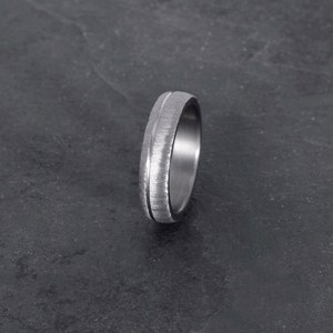 May include: A silver ring with a textured finish and a polished groove.