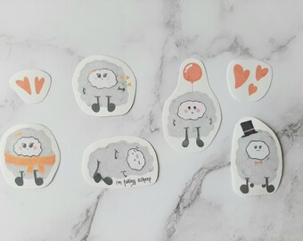 May include: Six gray and white cloud-shaped stickers with different expressions and accessories. One cloud has a flower, one has a balloon, one has a scarf, one has a hat, one has a bow tie, and one has a sleepy face. The stickers are on a white marble background.