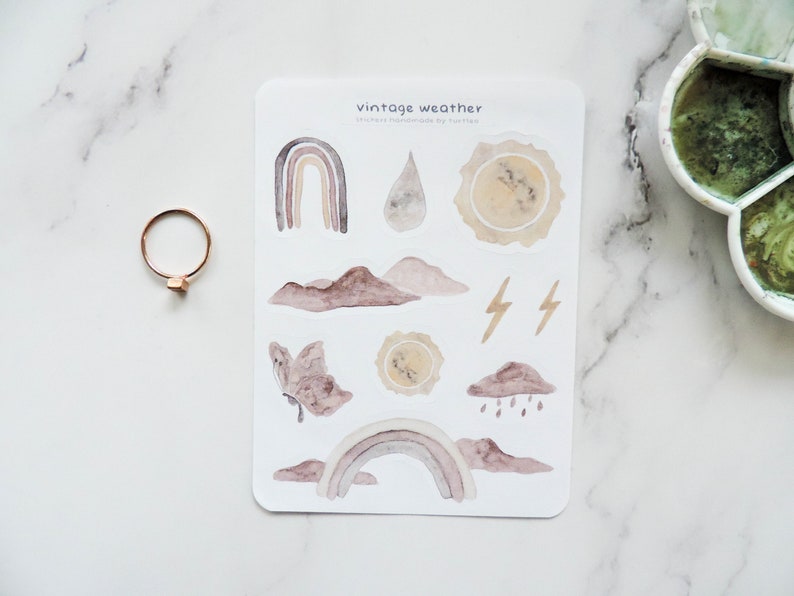 Puede incluir: Una hoja de pegatinas de clima vintage con ilustraciones de acuarela de arco&iacute;ris, nubes, gotas de lluvia, rayos y soles. Las pegatinas est&aacute;n hechas a mano por el vendedor y son perfectas para agregar un toque de fantas&iacute;a a tu planificador, diario o &aacute;lbum de recortes.