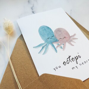 Pode incluir: Um cart&atilde;o de felicita&ccedil;&otilde;es com uma ilustra&ccedil;&atilde;o de aquarela de dois polvos se abra&ccedil;ando. O texto do cart&atilde;o diz "you octopi my heart".
