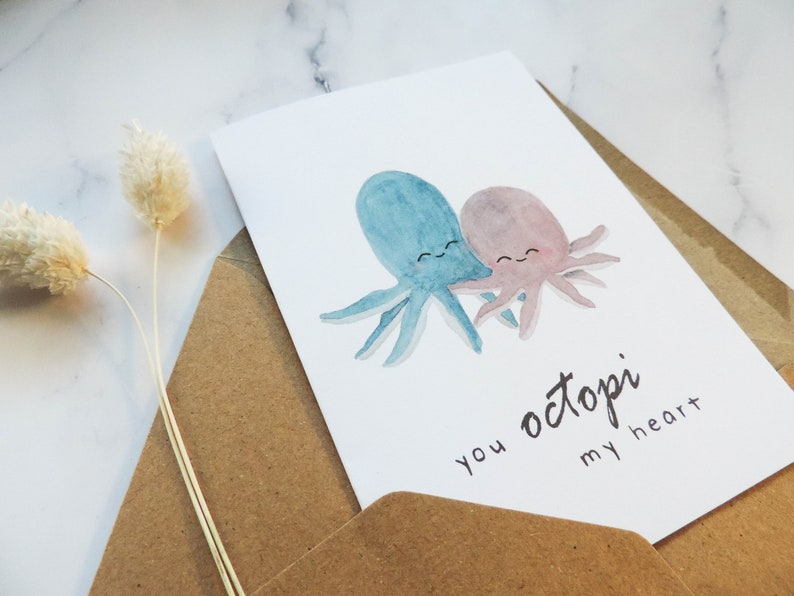 Pode incluir: Um cart&atilde;o de felicita&ccedil;&otilde;es com uma ilustra&ccedil;&atilde;o de aquarela de dois polvos se abra&ccedil;ando. O texto do cart&atilde;o diz "you octopi my heart".