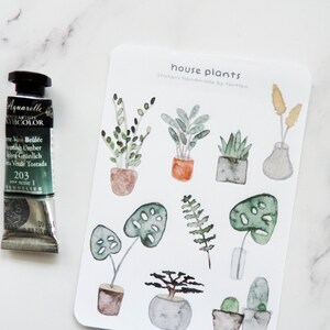May include: A sheet of stickers featuring watercolor illustrations of house plants in pots. The stickers are labeled "house plants" and "stickers handmade by turtl".