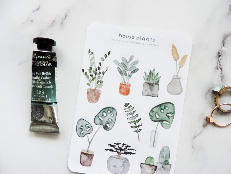 May include: A sheet of stickers featuring watercolor illustrations of house plants in pots. The stickers are labeled "house plants" and "stickers handmade by turtl".