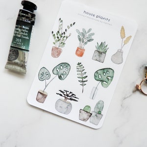 May include: A sheet of stickers featuring watercolor illustrations of house plants in pots. The stickers are labeled "house plants" and "stickers handmade by tuttled".