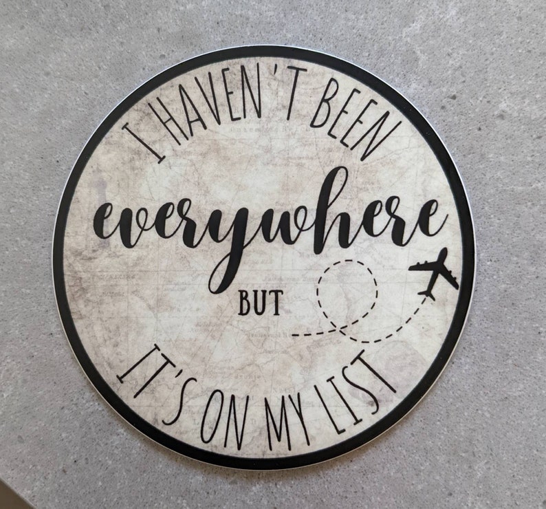 May include: Round sticker with a vintage map background. The sticker says "I haven't been everywhere but it's on my list" with a plane and a dotted line representing a flight path.