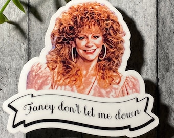 Könnte beinhalten: Ein weißer Aufkleber mit einem Porträt einer Frau mit langen roten Haaren und dem Text "Fancy don't let me down" auf einem Banner.