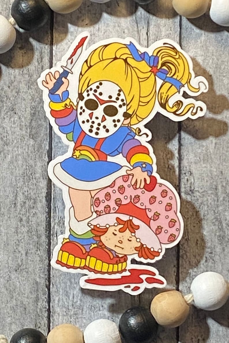 May include: A sticker featuring a cartoon character with a rainbow dress and a hockey mask holding a knife over another cartoon character with a strawberry dress and a red hat.