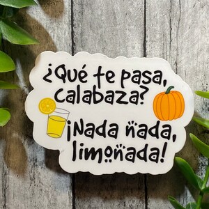 Op de afbeelding: Witte sticker met een spraakballonontwerp. De tekst luidt "¿Qué te pasa, calabaza? ¡Nada nada, limonada!" met een glas limonade en een pompoenillustratie.