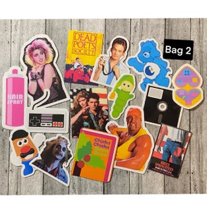 May include: A collection of vintage stickers featuring characters and movie titles from the 1980s. The stickers include images of Hulk Hogan, a Care Bear, a Nintendo Entertainment System, a  'Dead Poets Society' movie poster, and a 'Chicka Chicka Boom Boom' book.