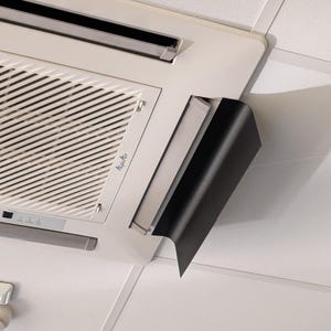 Op de afbeelding: Een witte airconditioner die aan het plafond is gemonteerd met een zwarte plastic afdekking over de ventilatieopening.