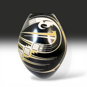 May include: A smooth, black, egg-shaped vase featuring a stylized white and gold bird motif. The design includes intricate geometric patterns, thin horizontal lines, and a prominent avian head silhouette wrapping around the curved surface.