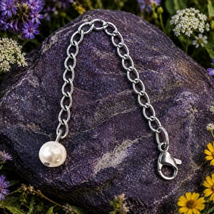 May include: A silver-toned metal chain extender featuring a series of oval links. One end of the chain is finished with a single round, off-white pearl bead, while the other end is equipped with a secure silver-toned lobster claw clasp.
