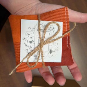 May include: A small orange and white checkered fabric pouch tied with twine and a tag that says "Solace".