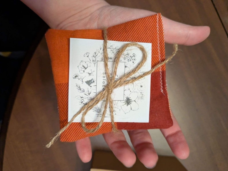 May include: A small orange and white checkered fabric pouch tied with twine and a tag that says "Solace".