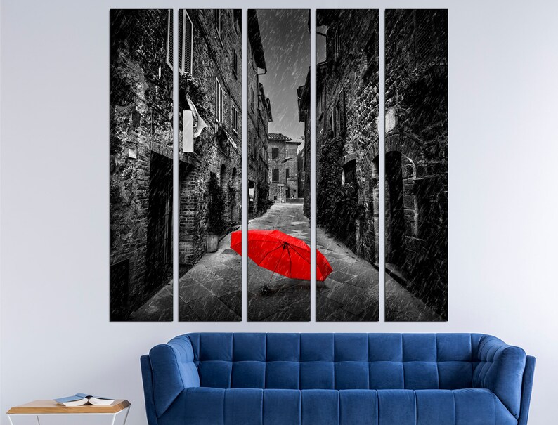 May include: A black and white photograph of a narrow alleyway in a city. The alleyway is lined with brick buildings and there is a red umbrella lying in the middle of the street.
