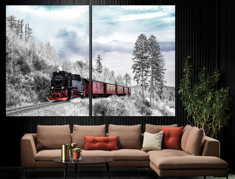 May include: A two-panel canvas print depicting a vintage steam train traveling through a snowy forest. The train is black and red, with several red passenger cars. The forest is in black and white, with a blue sky in the background.