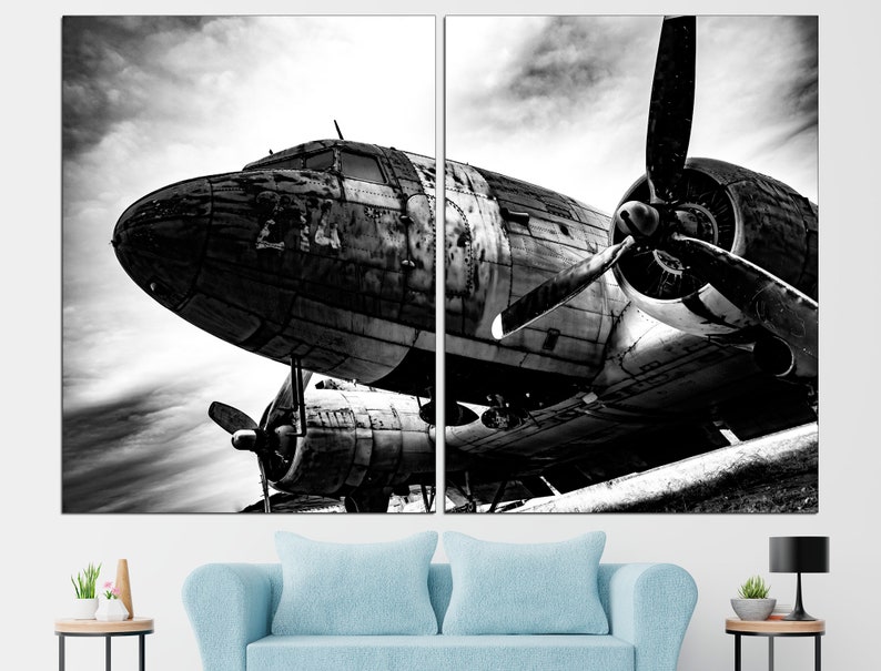 May include: A black and white photograph of a vintage airplane with a propeller. The airplane is sitting on the ground with the propeller facing the camera. The airplane is weathered and has a lot of detail.