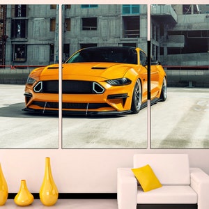 May include: A bright yellow sports car parked in a concrete urban setting. The car has a black grille and black wheels. The car is in focus, while the background is blurred.