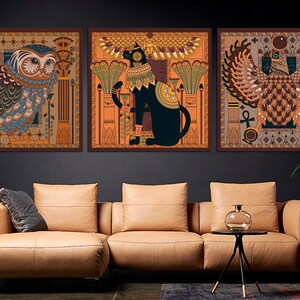 May include: Three framed prints with an Egyptian theme. The first print features an owl with intricate details, the second print features a cat with wings, and the third print features a winged creature with a crown.