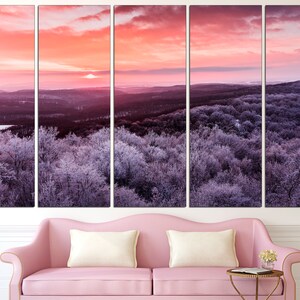 May include: A panoramic view of a snow-covered forest at sunrise. The sky is a vibrant pink and orange, with the sun peeking over the horizon. The trees are covered in a layer of frost, giving them a silvery appearance.