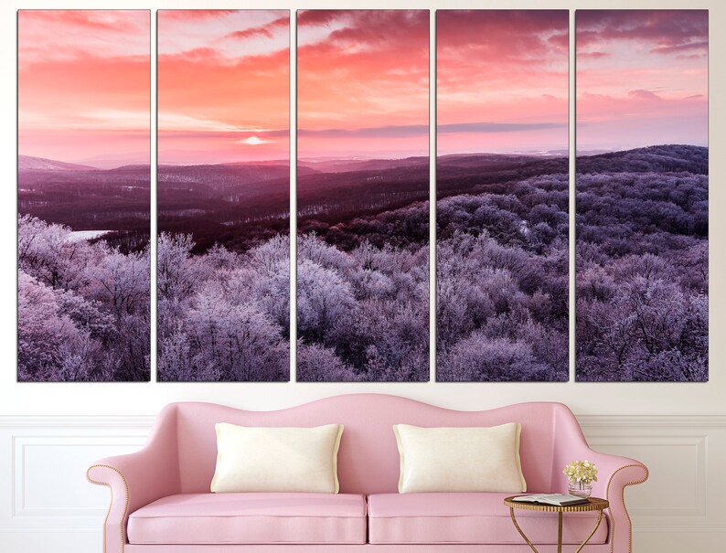 May include: A panoramic view of a snow-covered forest at sunrise. The sky is a vibrant pink and orange, with the sun peeking over the horizon. The trees are covered in a layer of frost, giving them a silvery appearance.