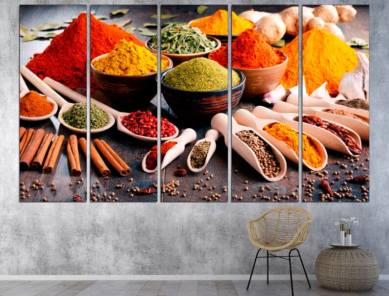 May include: A close-up of a variety of spices in bowls and spoons, including red pepper flakes, turmeric, cinnamon sticks, and coriander seeds. The spices are arranged on a wooden surface.