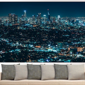 Puede incluir: Una vista a&eacute;rea nocturna de un horizonte urbano con muchos edificios y luces. La ciudad est&aacute; iluminada con un brillo azul, y los edificios son altos y delgados. La ciudad est&aacute; rodeada de una zona boscosa oscura.