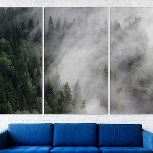 May include: A three-panel canvas print featuring a misty forest scene. The image shows a dense forest with tall trees and a thick layer of fog rolling through the trees. The colors are muted and the overall effect is calming and serene.