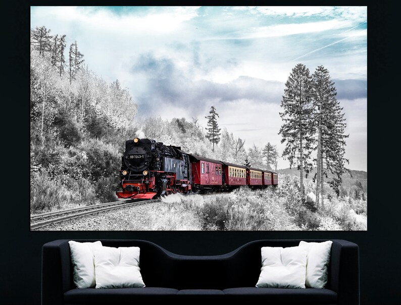 May include: A black and red steam train travels along a track through a snowy, black and white forest. The train has several red passenger cars. The sky is a pale blue with some clouds. The image is a print on a canvas.