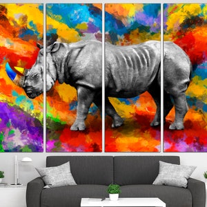 May include: A black and white rhinoceros stands on a colorful abstract background. The background is a mix of bright colors, including red, orange, yellow, green, blue, and purple. The rhinoceros is in the center of the image, and its horn is painted in bright colors.